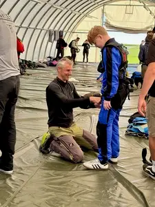 Der Tandemmaster von Skydive Altenstadt legt Vincent Stiffel im Hangar das Gurtzeug an