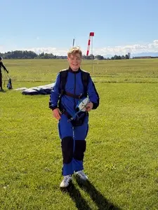 Vincent Stiffel lacht nach der Landung im blauen Sprunganzug auf dem Landefeld von Skydive Altenstadt