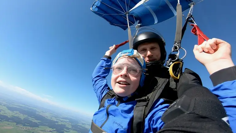 Vincent Stiffel und sein Tandemmaster unter dem geöffneten Fallschirm über Altenstadt, strahlend blauer Himmel