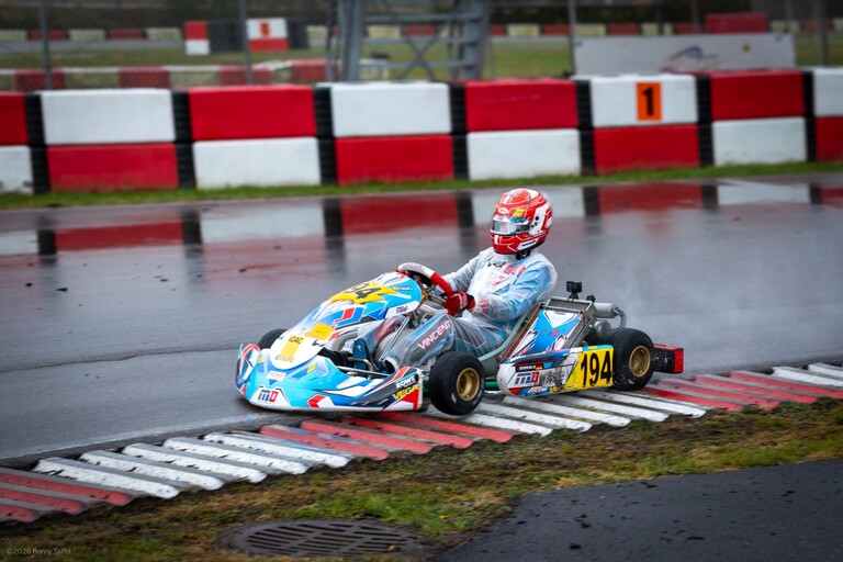 Vincent Stiffel mit der Startnummer 194 im Regenoverall über den nassen Curb in Wackersdorf